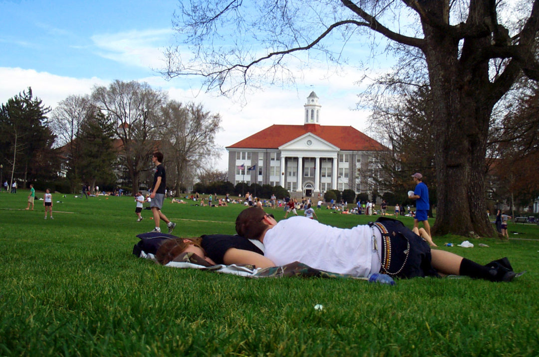 Students resting on a lawn of a college campus