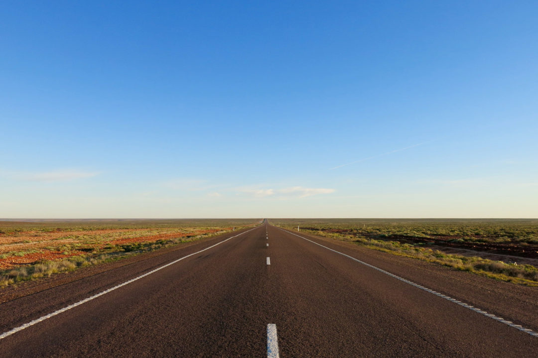 A long stretch of empty highway with fields on both sides