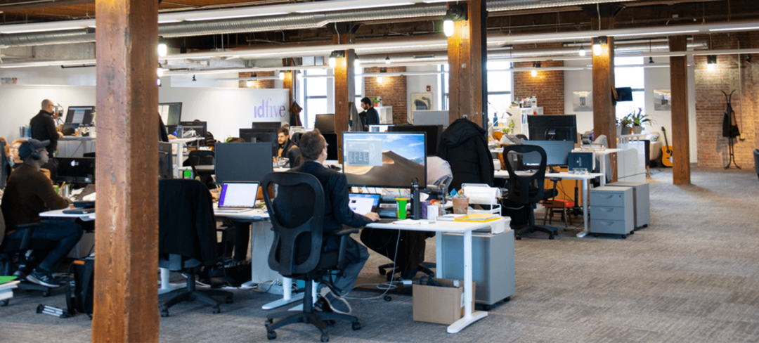 idfive office: Wood ceiling, exposed brick walls, lantern style lighting, desks and computers.