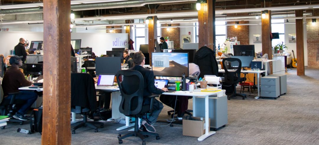 idfive office: Wood ceiling, exposed brick walls, lantern style lighting, desks and computers.