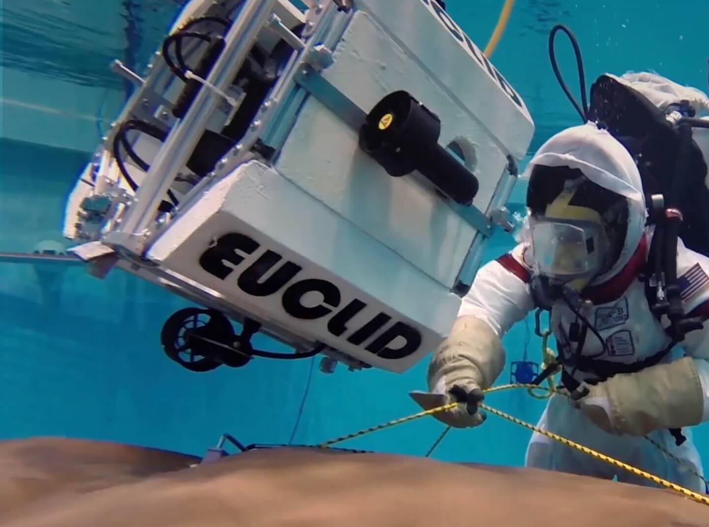A University of Maryland student in a space suit ties rope during an underwater equipment test