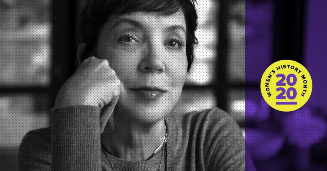 A woman in black-and-white looks out at the camera, her head resting lightly on her hand.