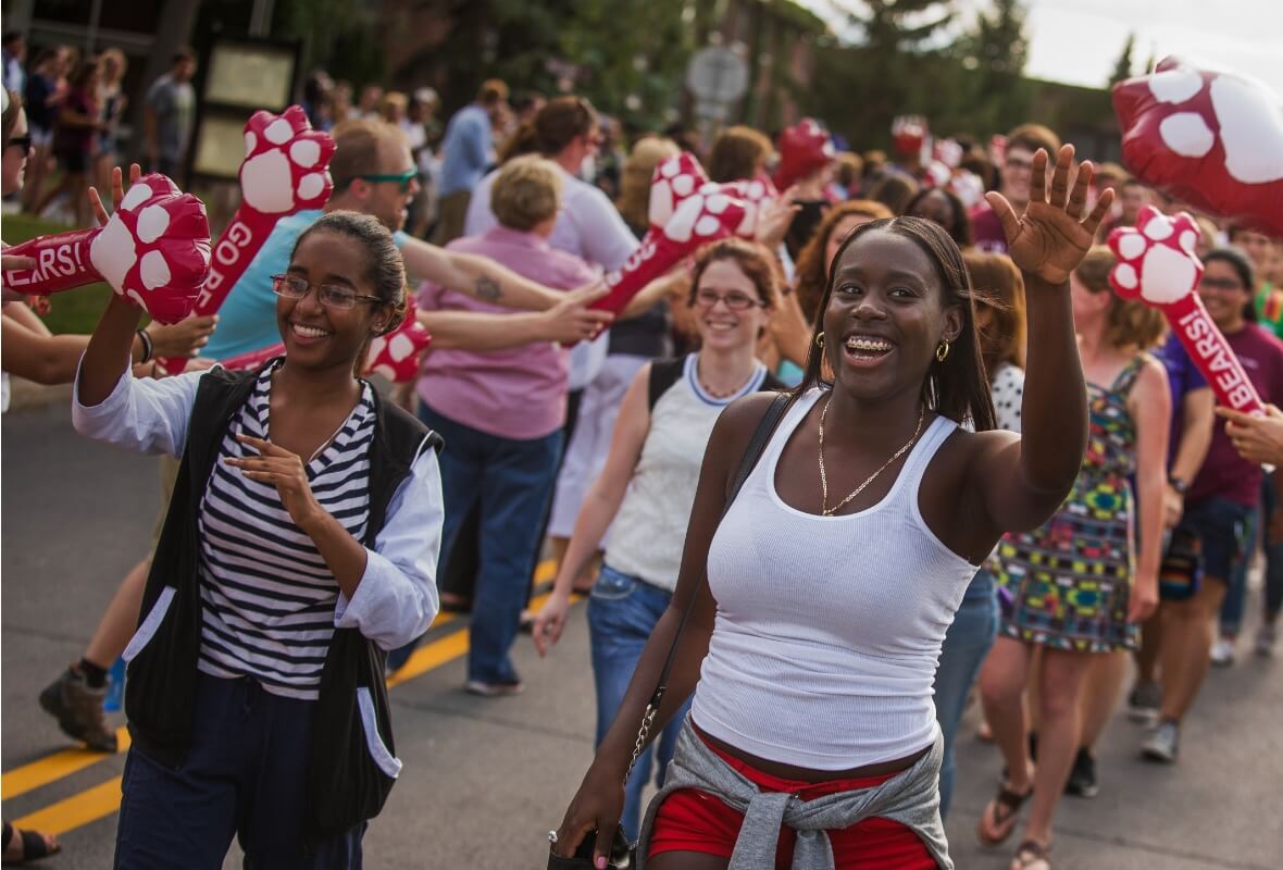 Students exchange high fives and wave thunder sticks at a parade on the SUNY Potsdam campus