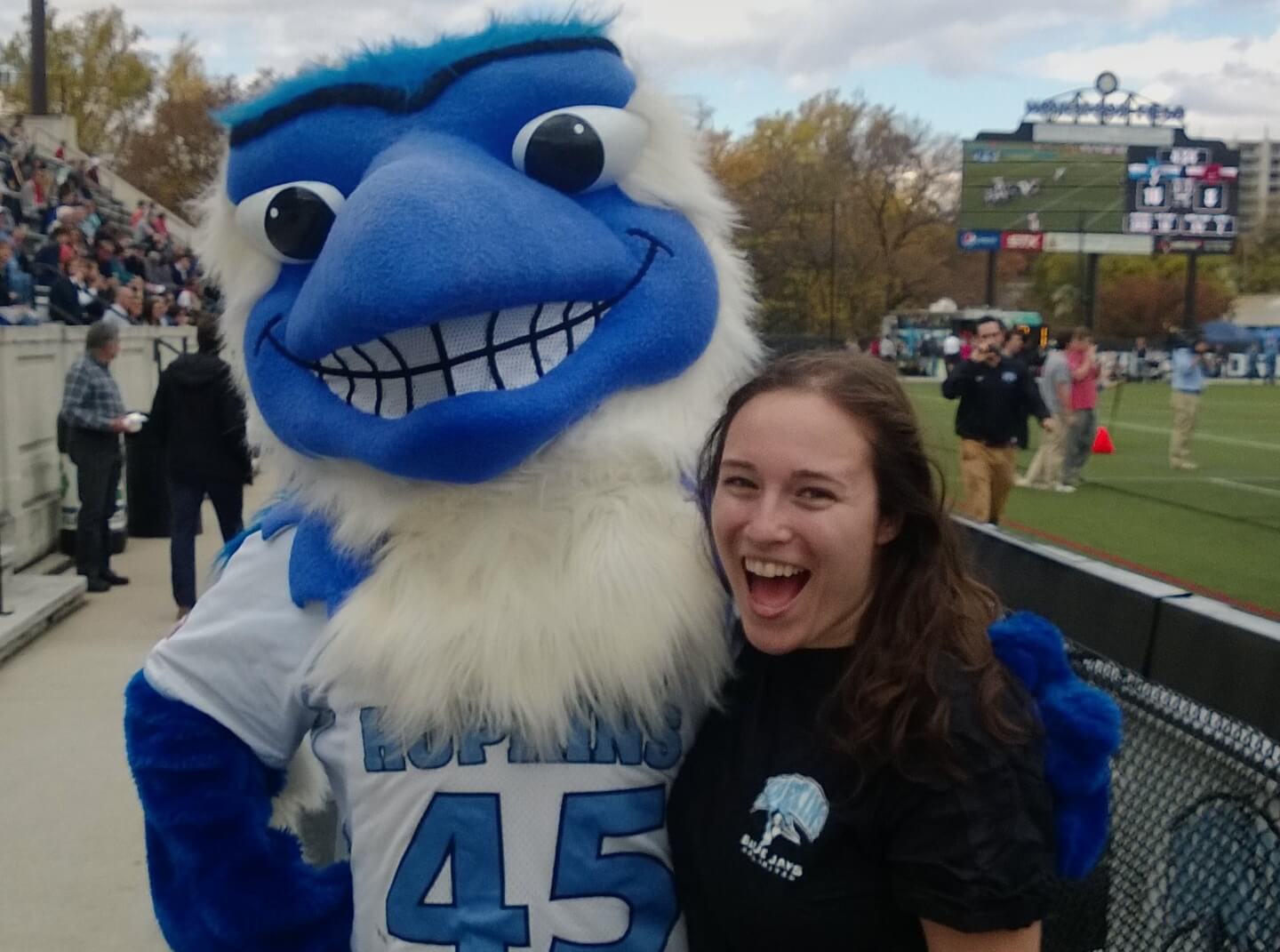 A Hopkins student poses with the Blue Jay mascot during a lacrosse game at Homewood stadium