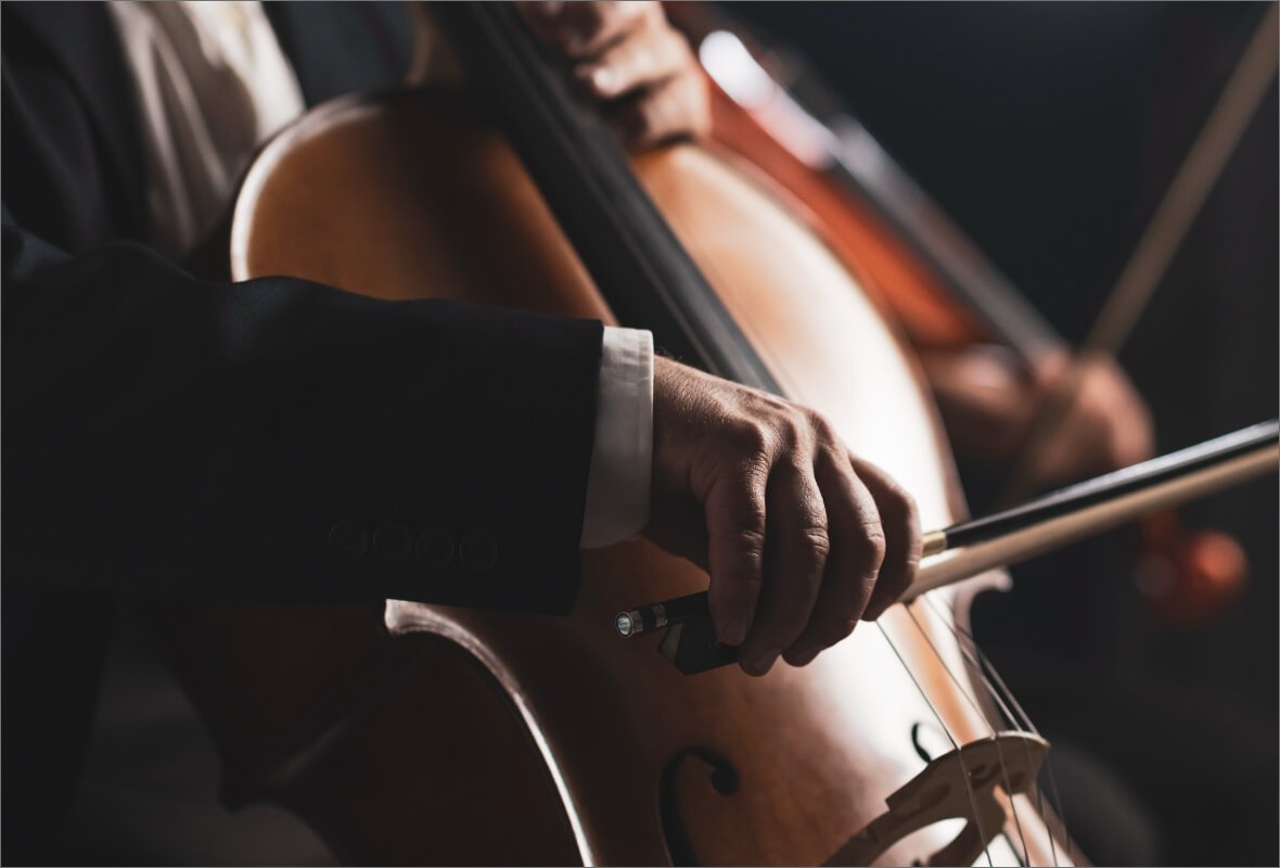 A seated musician in formal wear bows a cello