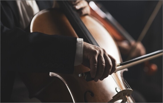 A seated musician in formal wear bows a cello