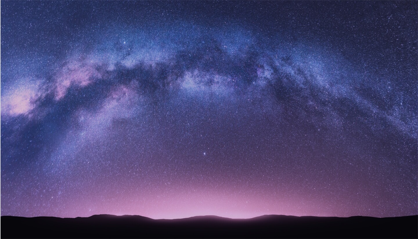 Nighttime photo of the Milky Way visible over a mountainous horizon
