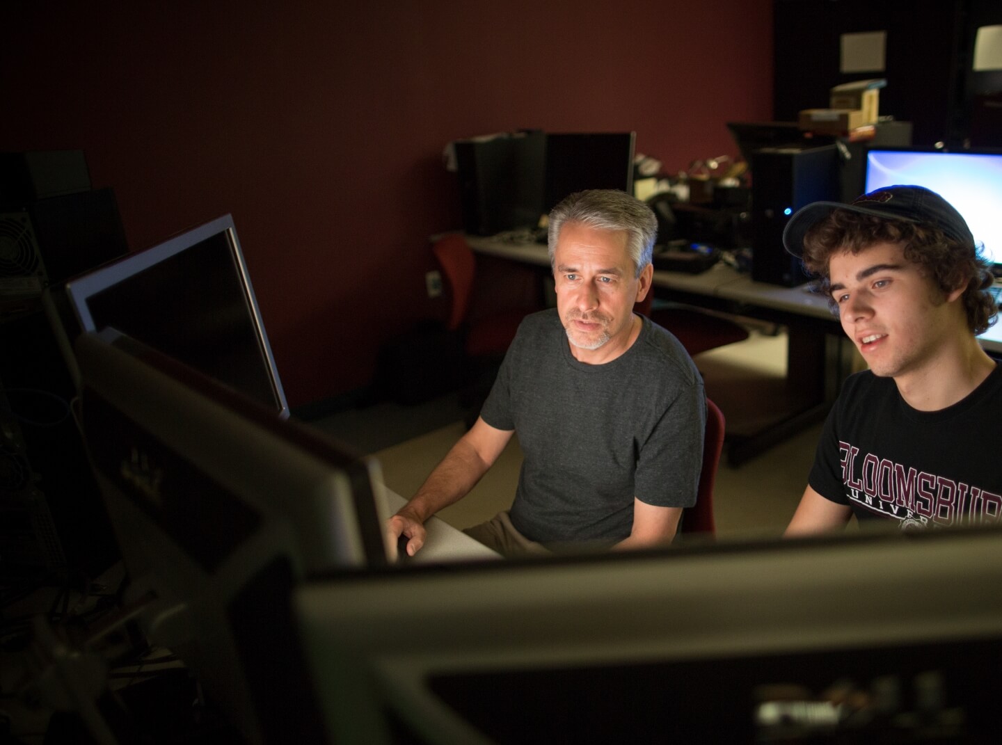 Bloomsburg professor and student sit in front of monitors at an on-campus media editing station
