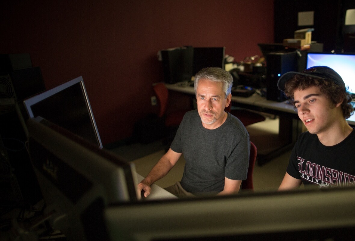 Bloomsburg professor and student sit in front of monitors at an on-campus media editing station