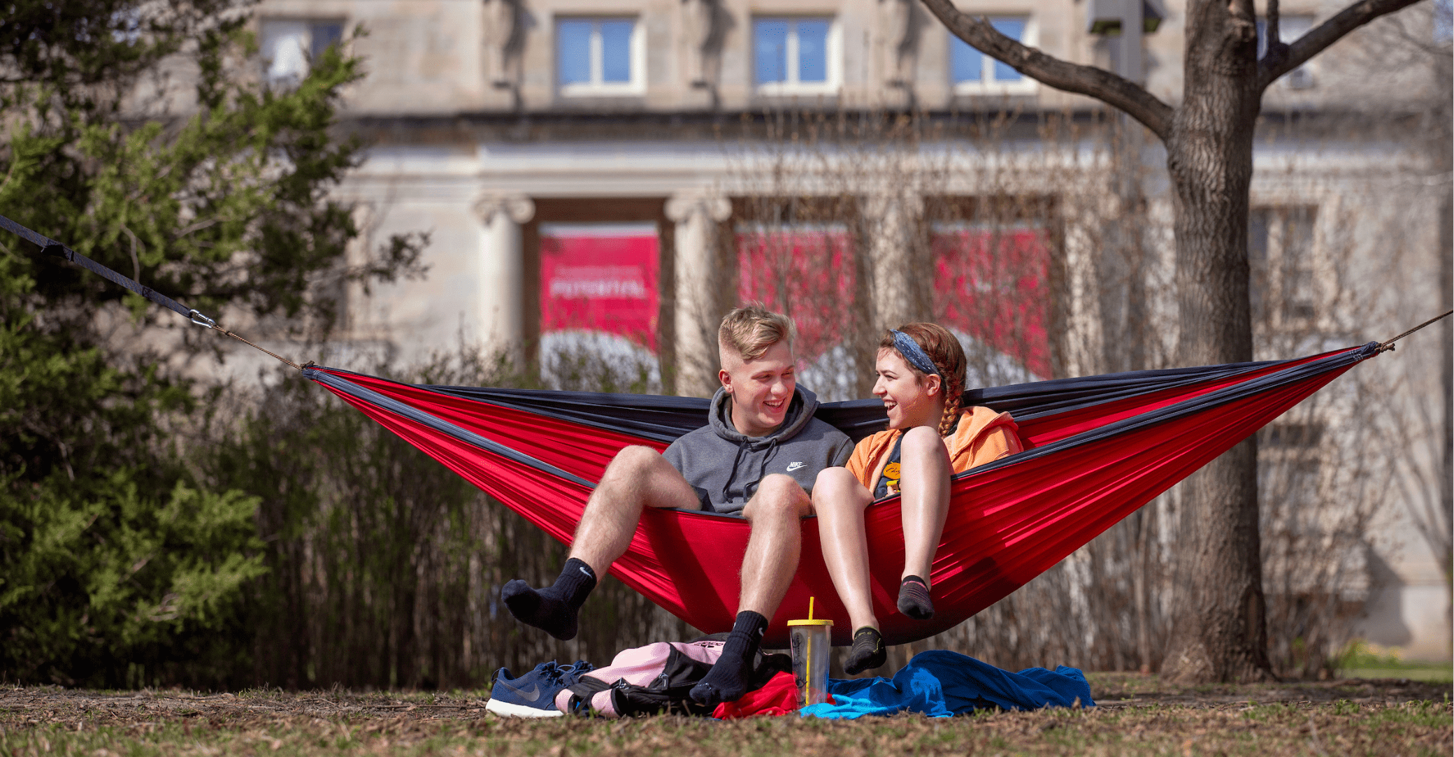 Students in hammock enjoying ISU campus grounds.