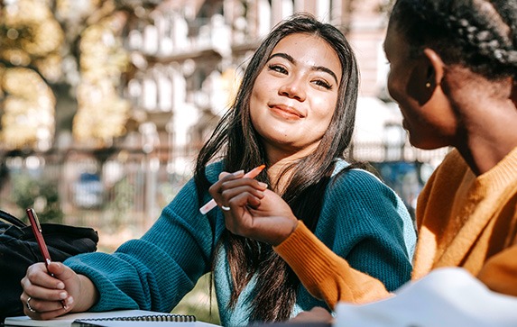 Two young female students working together on school work outside.